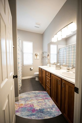 HomeRoots 4' Blue and Pink Round Abstract Power Loom Area Rug in Wooden and Grey Bathroom